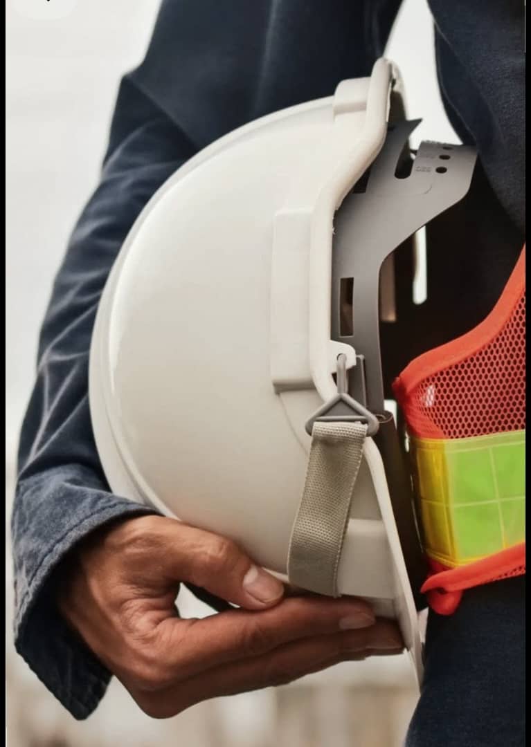 Worker holding hard hat and high-visibility safety vest
